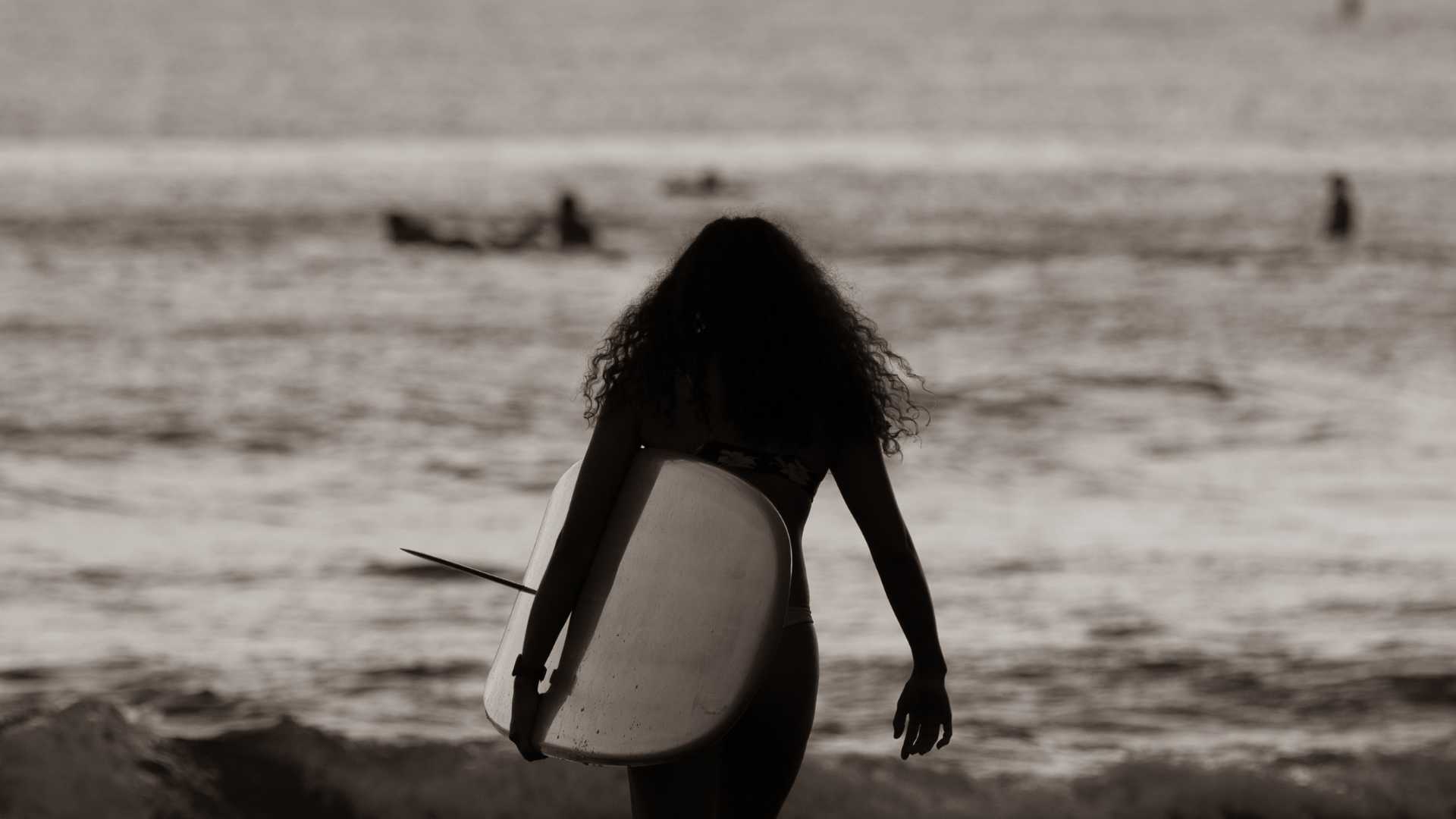 Surfeuse avec sa planche de surf sous le bras